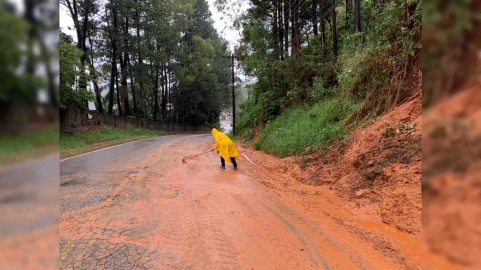 Homem fazendo a limpeza de terra que caiu na via em Várzea Paulista