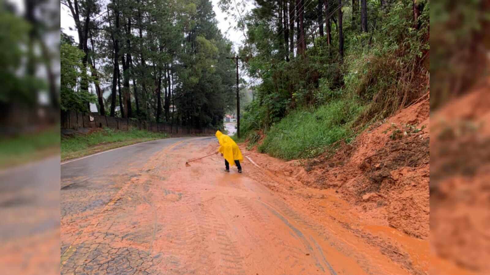 Homem fazendo a limpeza de terra que caiu na via em Várzea Paulista