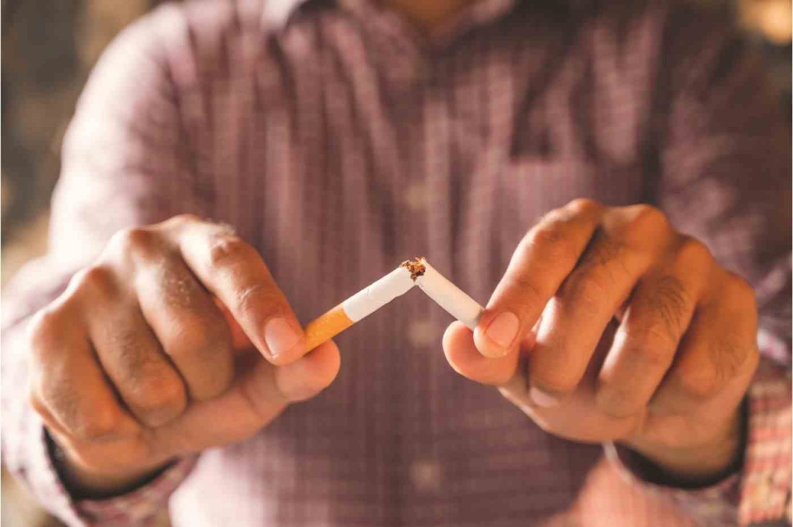 Homem quebrando um cigarro ao meio, simbolizando o Dia de Mundial Sem Tabaco e a decisão de parar de fumar.