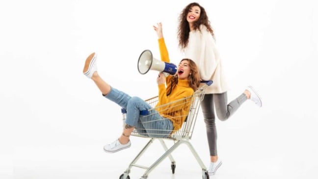 Uma mulher empurrando a outra dentro de um carrinho de compras