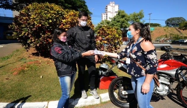 Foto de motoboys pegando máscaras de proteção