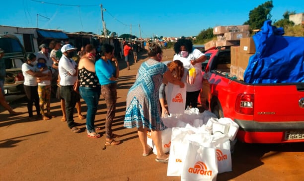 Fila de famílias retirando doações em caçamba de carro