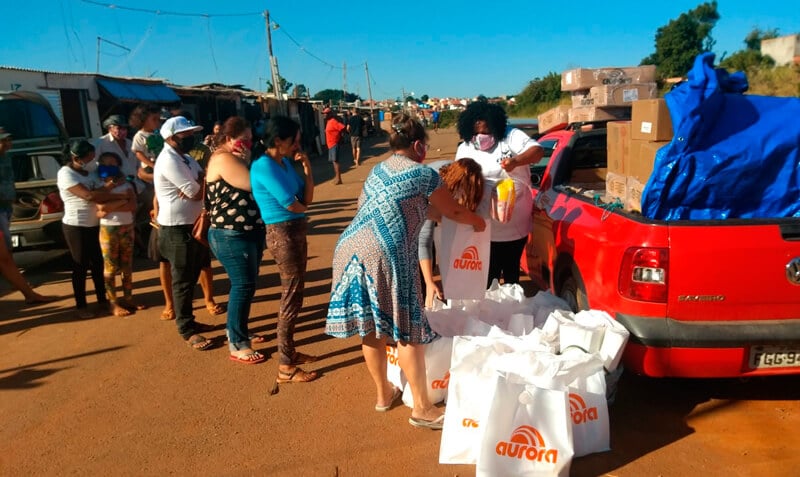 Fila de famílias retirando doações em caçamba de carro