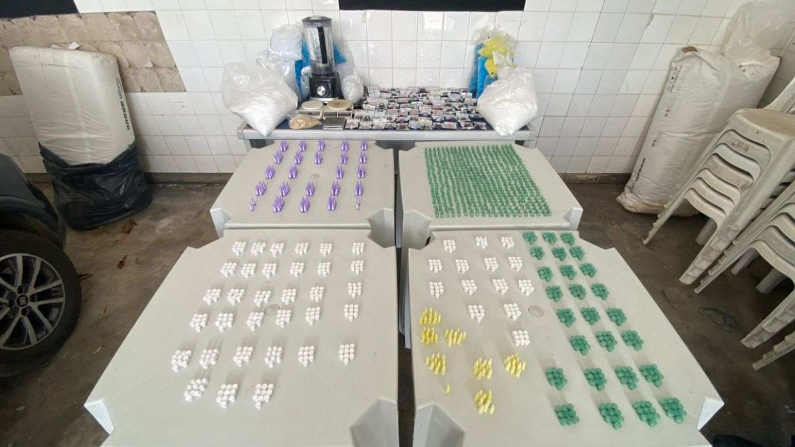 Mesa com dezenas de porções de drogas embaladas, balanças de precisão, sacos com pó branco e utensílios usados no preparo, apreendidos em operação da GM e PM em Itatiba.