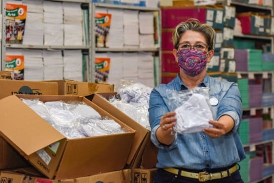 Mulher segurando máscara e caixas com máscara foram doadas a educação de Jundií