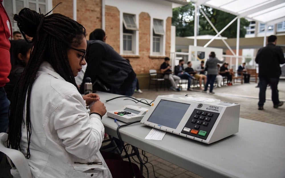 Mesária em local de votação com urna eletrônica