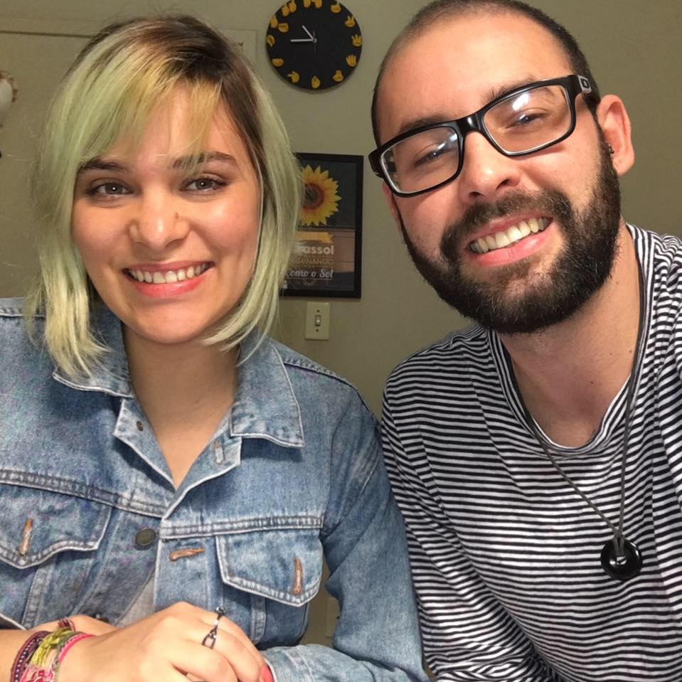 Mulher loira abraçada com homem barbado de óculos