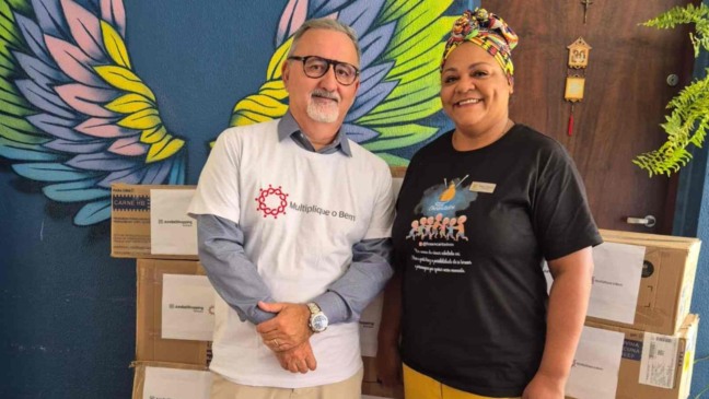 Doação do JundiaíShopping ao Projeto Fios Encantados em Jundiaí, com representantes posando em frente às caixas de alimentos e roupas.