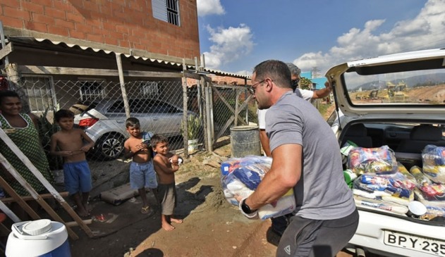 Foto de pessoas entregando cestas básicas