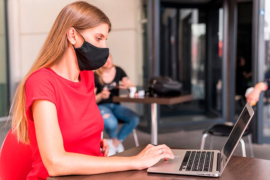 Mulher com máscara utiliza notebook. (Foto: Divulgação/Freepik)