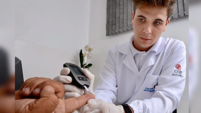 Profissional de saúde colhe gota de sangue de dedo de caminhoneiro para a realização de exames