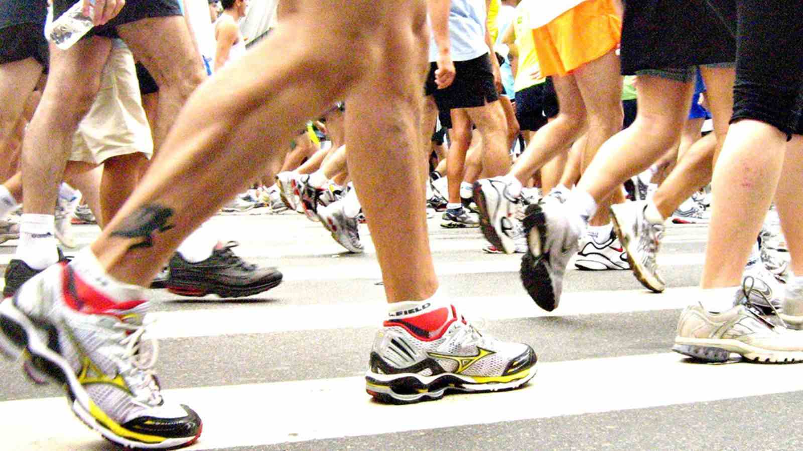 Pernas de corredores em movimento durante uma corrida de rua.