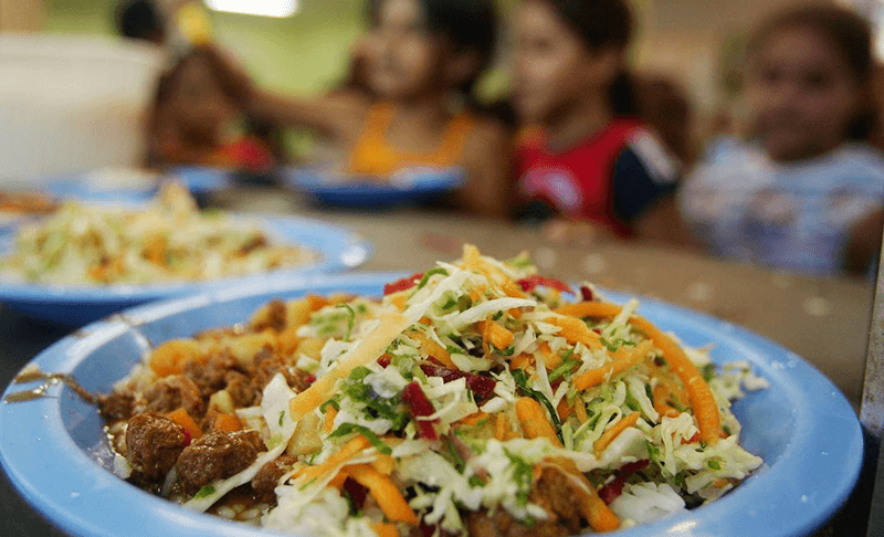 Prato de merenda, com crianças desfocadas atrás