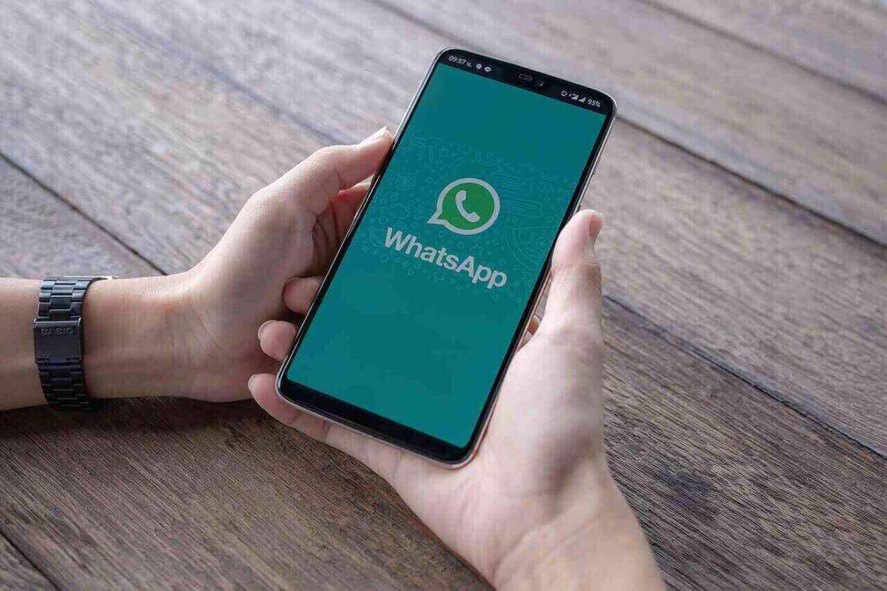 Mãos segurando o celular com a tela aberta no Aplicativo WhatsApp