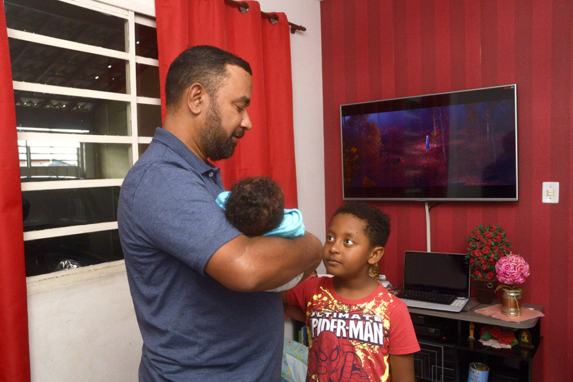 homem carregando um bebê ao lado de uma criança