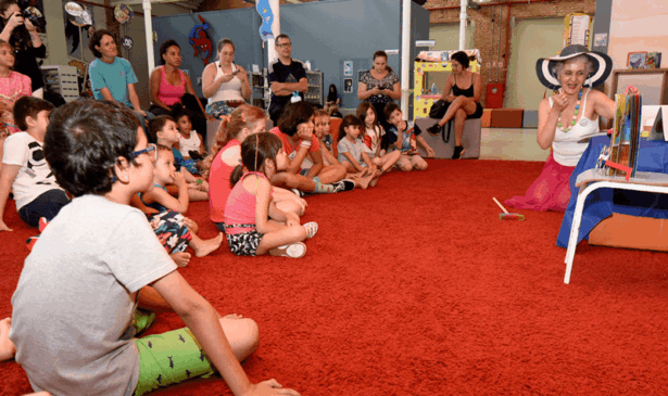 Carmen, a contadora de história, apresenta um livro a um grupo de crianças