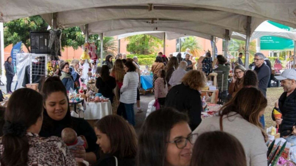Evento ao ar livre, sob uma tenda, com várias pessoas circulando entre barracas de artesanato e produtos locais de Jundiaí. Evento ao ar livre, sob uma tenda, com várias pessoas circulando entre barracas de artesanato e produtos locais de Jundiaí.