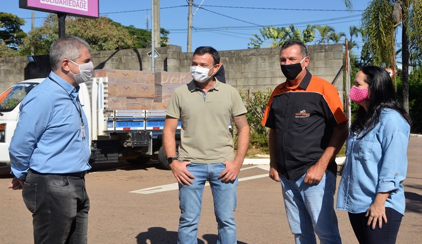 grupo de pessoas em frente de caminhão com cestas básicas