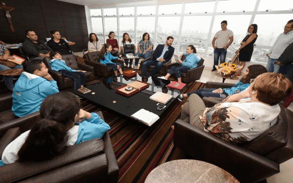Crianças e pais sentados em sofás e poltronas no Gabinete do prefeito Luiz Fernando Machado