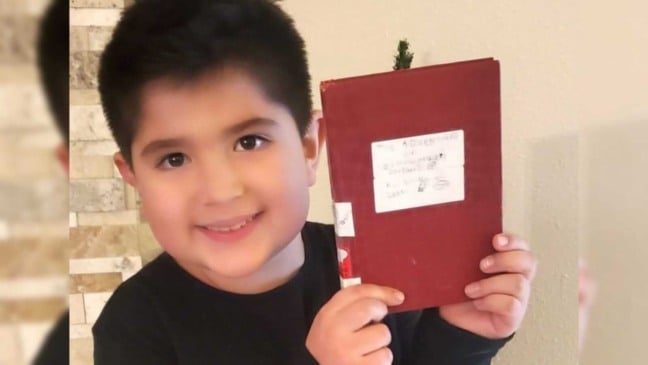 menino segurando o livro que ele escreveu