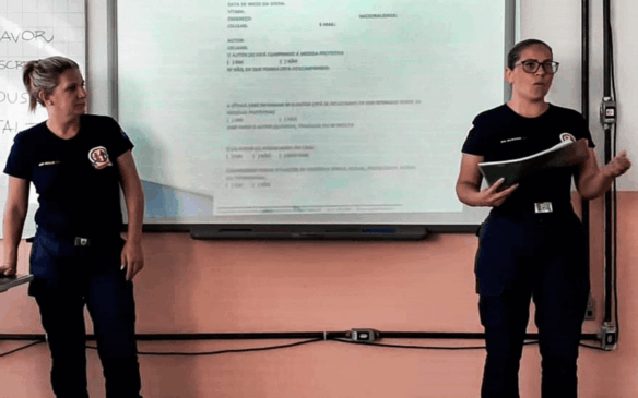 Duas guardas falam em frente a datashow