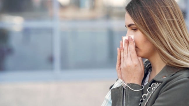 Mulher limpando o nariz.