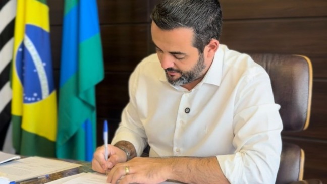 Gustavo Martinelli assinando papel.