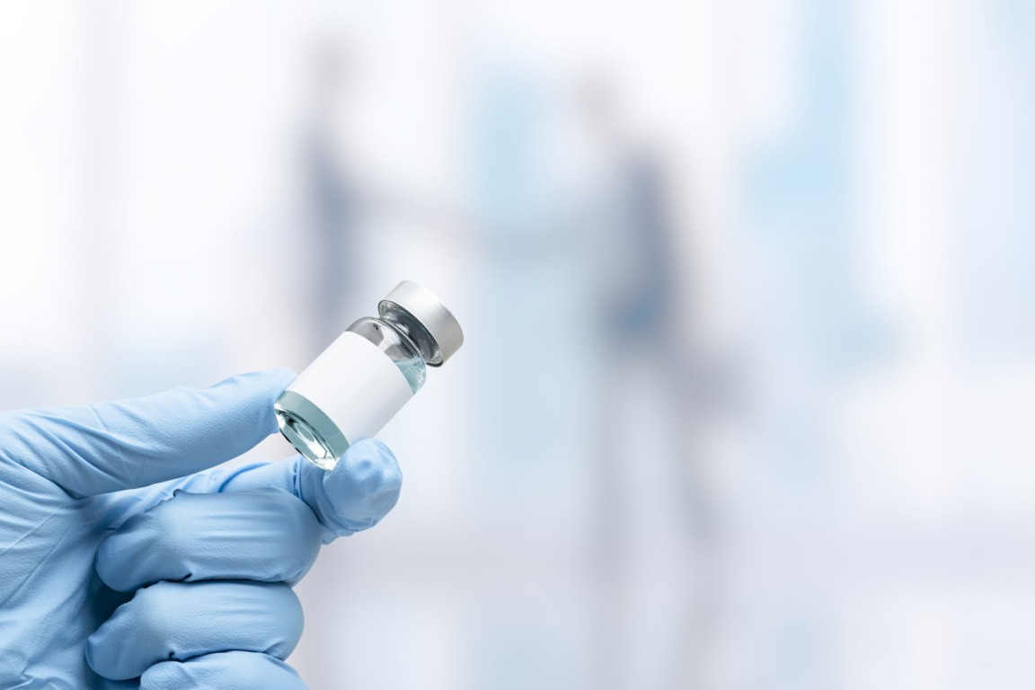 Hand in medical glove holding a vaccine vial