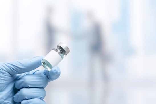 Hand in medical glove holding a vaccine vial