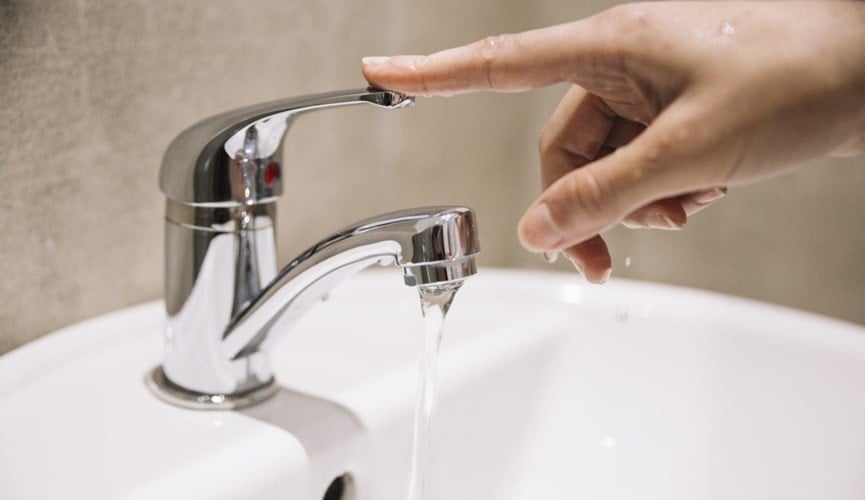 Pessoa abre torneira com água