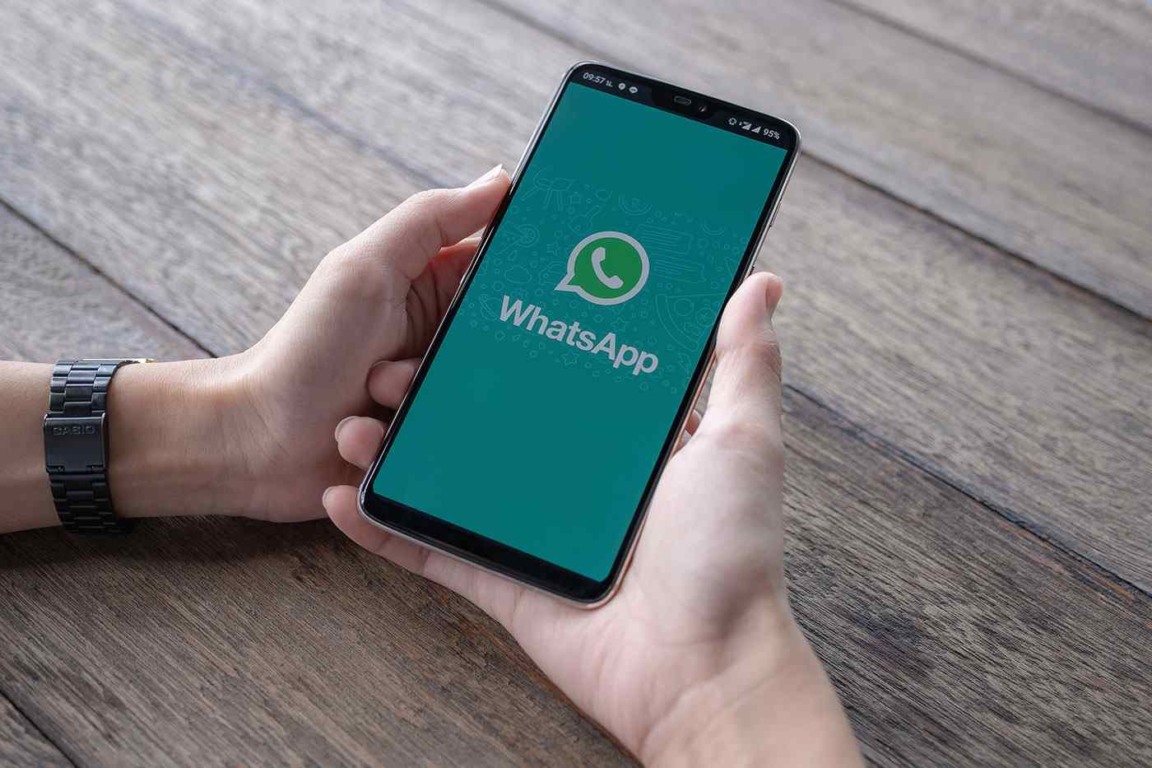 Homem segurando um smartphone com whatsapp aberto na tela