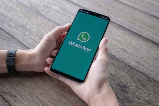 Homem segurando um smartphone com whatsapp aberto na tela