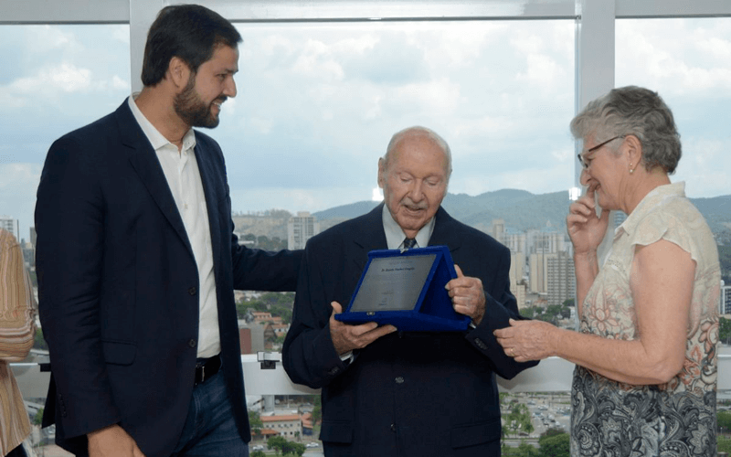À esquerda, o prefeito Luiz Fernando Machado, ao centro, o médico homenageado com sua placa comemorativa, e ao lado, membro da família.