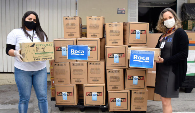 Mulheres ao lado de caixas com doações da Roca