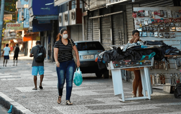 Mulher anda com máscara na calçada