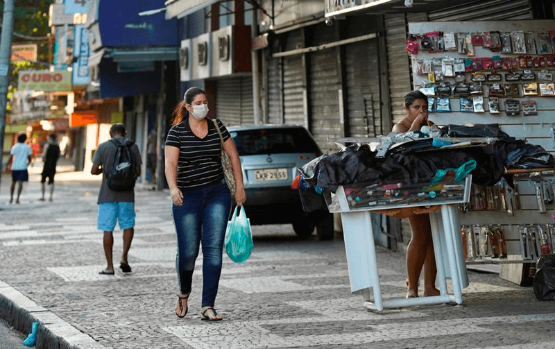 Mulher anda com máscara na calçada