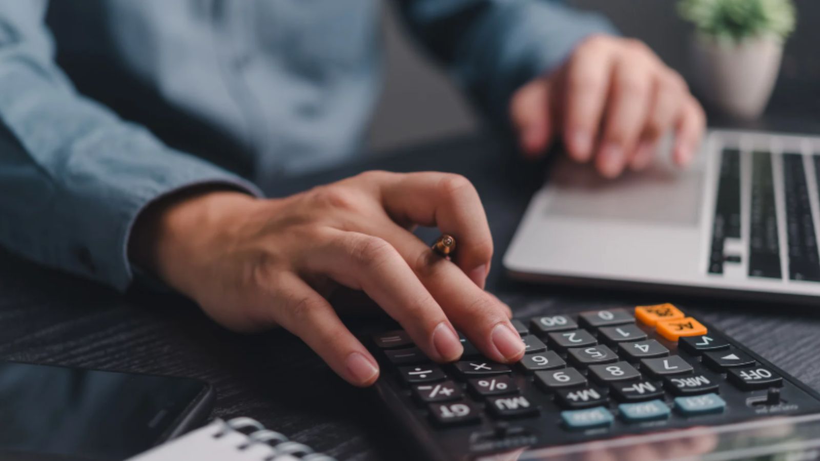 Homem mexendo em calculadora e computador.