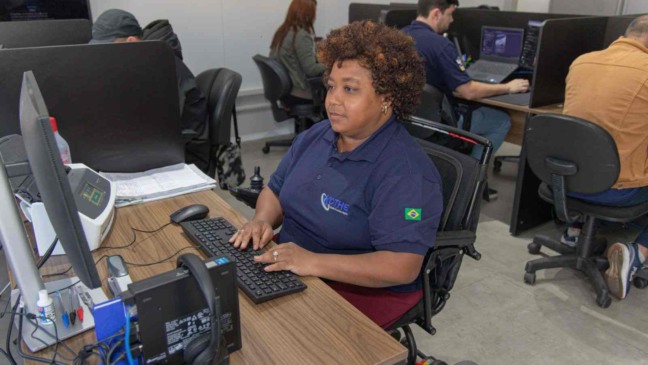Mulher cadeirante trabalha em frente ao computador em escritório da Kothe Logística, em Jundiaí, como exemplo de inclusão produtiva de pessoas com deficiência.