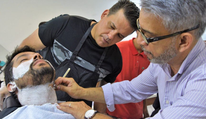 homem fazendo a barba com um ajudante