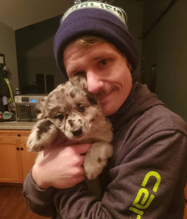 Homem com filhote de cachorro no colo