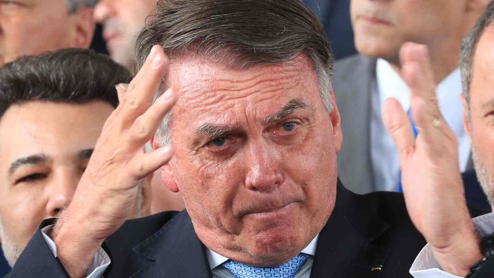 Ex-presidente Jair Bolsonaro com expressão séria e mãos levantadas próximo ao rosto, em gesto de preocupação, durante evento público.