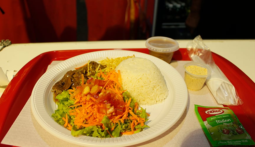 Arroz, salada, e bife em prato com feijão ao lado