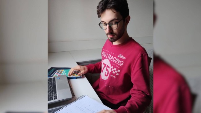 Jovem de Jundiaí estuda com livros e laptop.