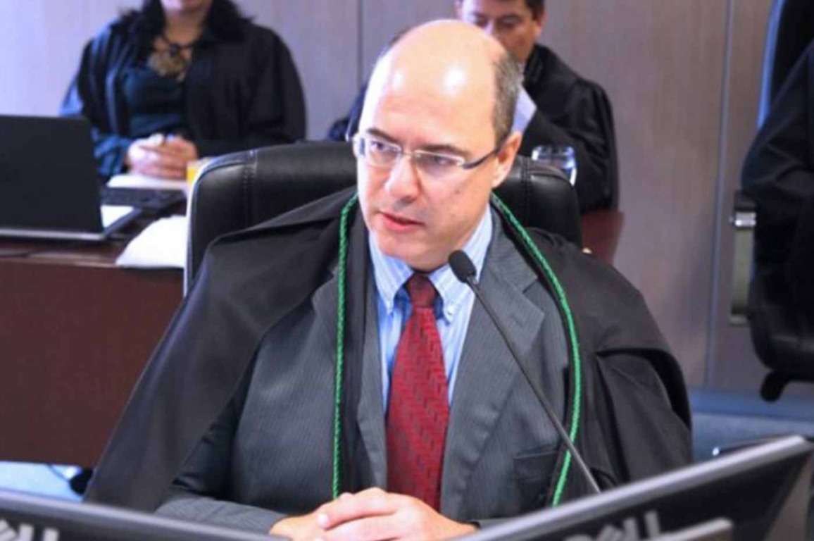 Juiz federal Wilson José Witzel, de terno e capa preta, fala em microfone durante sessão; destaque na política do Rio de Janeiro