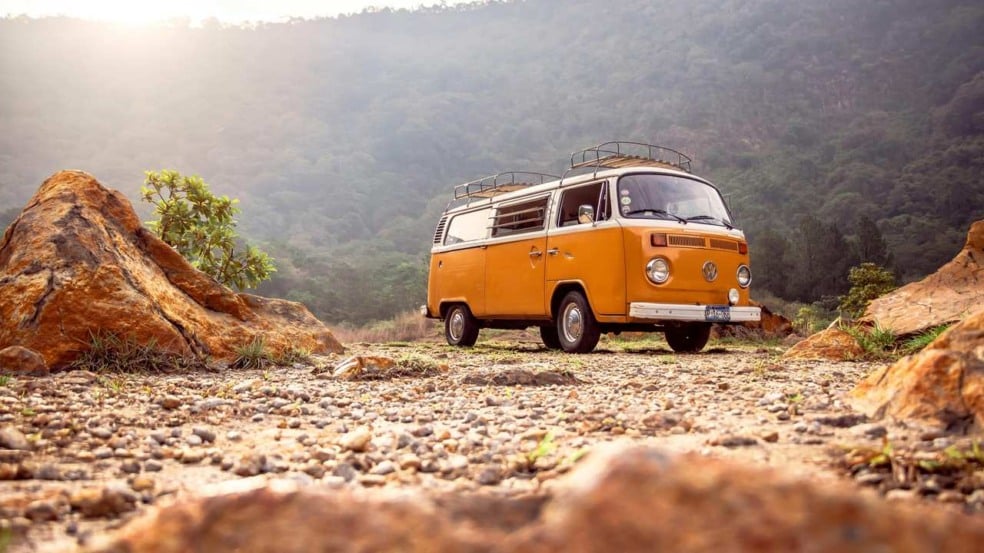 Kombi amarela em paisagem natural, ideal para viagens pelo Brasil.