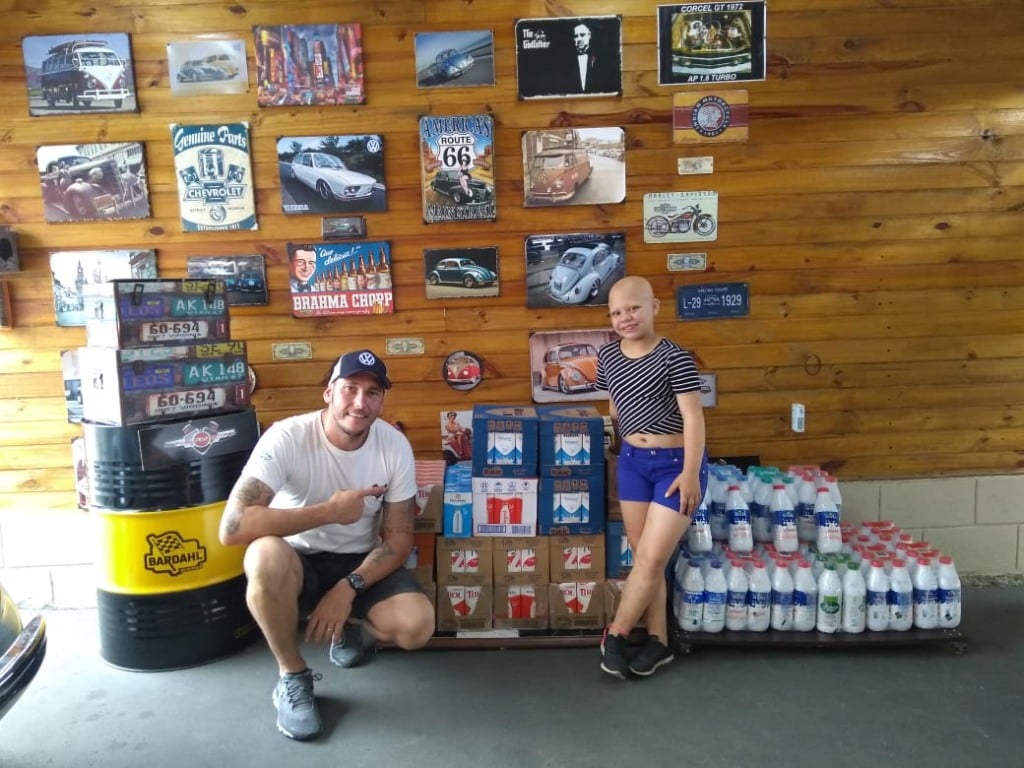 menina e homem perto de caixas de leite para doação