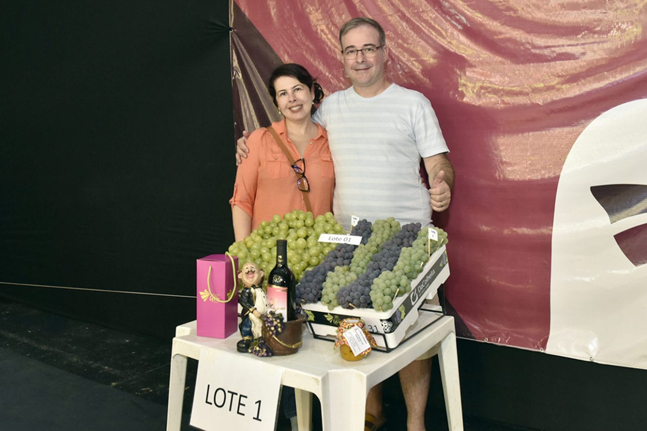 Casal com caixa de uva, pote de geleia e garrafa de vinho