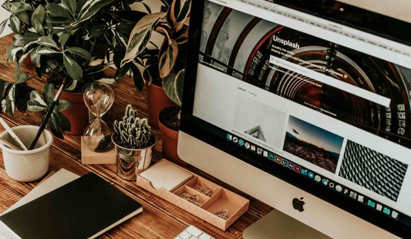 Espaço de trabalho organizado com iMac, plantas, caderno, ampulheta e acessórios, representando produtividade e design natural. Espaço de trabalho organizado com iMac, plantas, caderno, ampulheta e acessórios, representando produtividade e design natural.