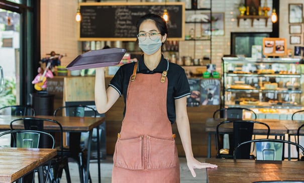 Garçonete trabalhando em lanchonete usando máscara