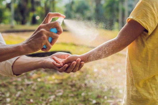 Mãe aplicando repelente em filho